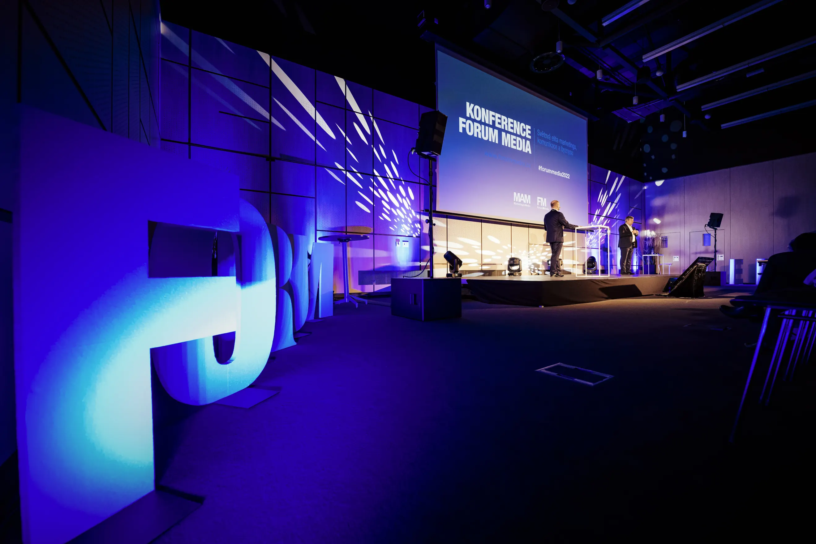 Pódium konference Forum Media osvětlené modrými reflektory