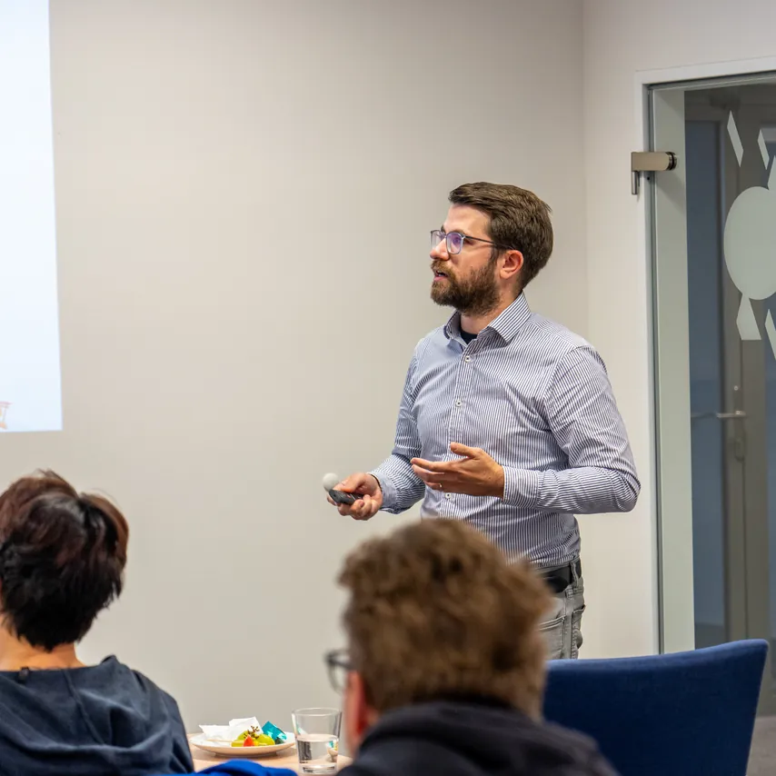 Přednášející před projekcí a účastníci u stolu na snídani ACOMWARE