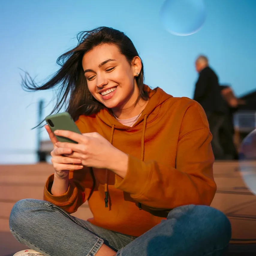 Žena v oranžové mikině si prohlíží telefon – vizuál O2